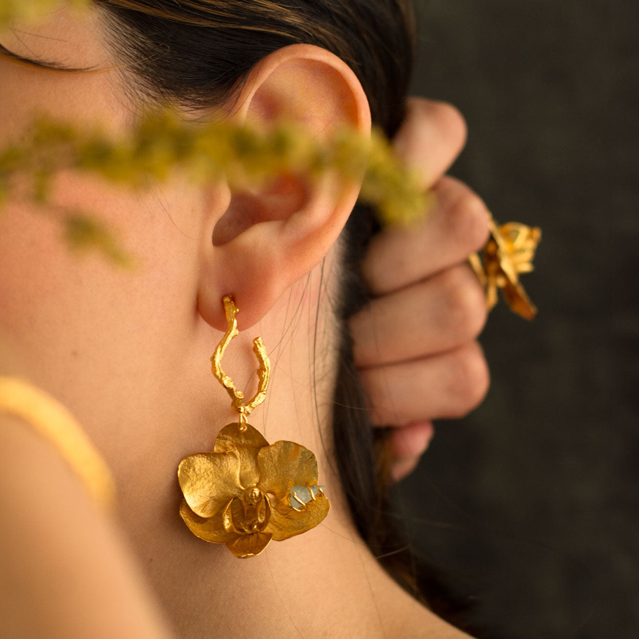 Aretes Candonga Orquídea Phalaenopsis Esmeralda en bronce bañado en oro de 24k, destacando flores naturales y esmeraldas colombianas