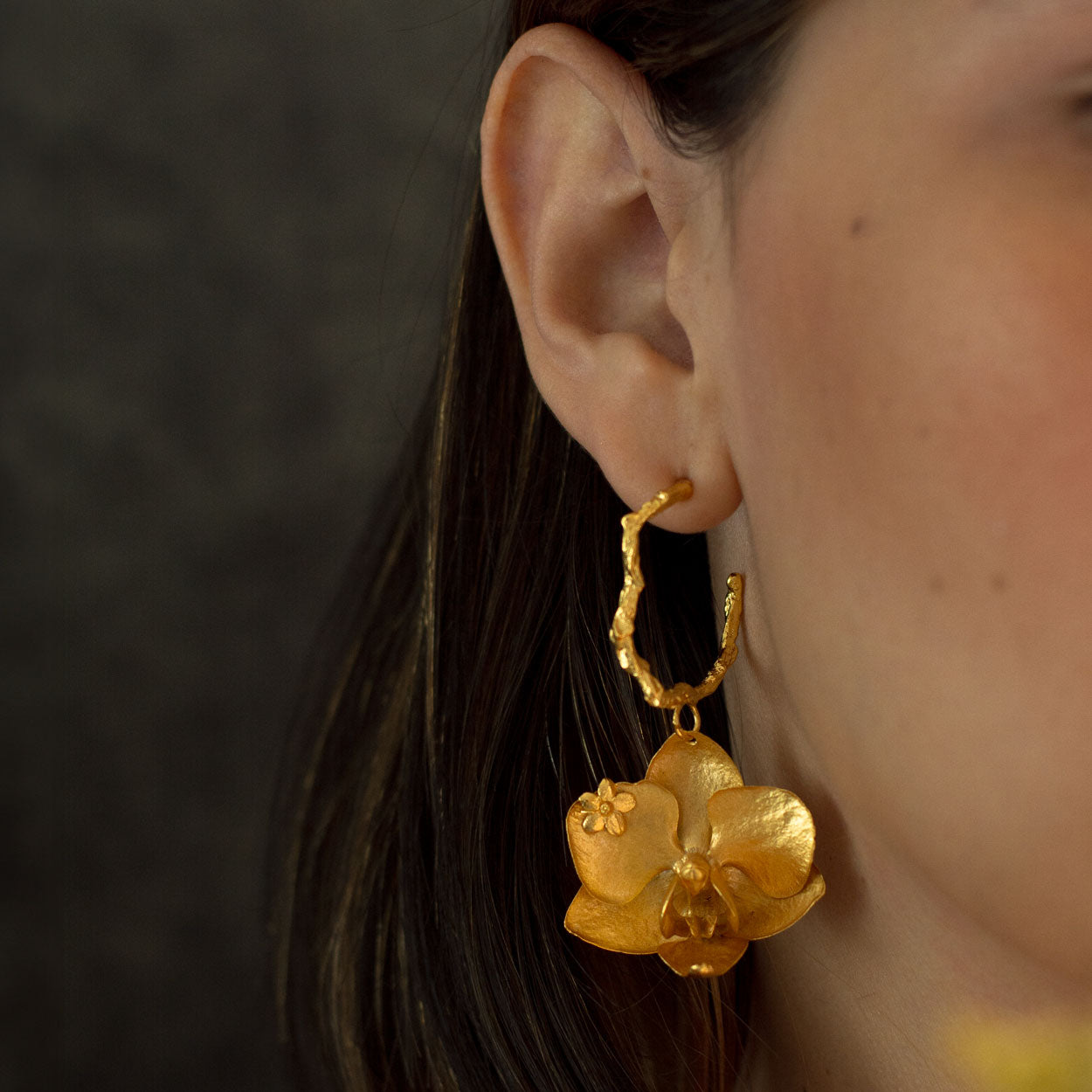 Aretes Candonga Orquídea Phalaenopsis Esmeralda en bronce bañado en oro de 24k, destacando flores naturales y esmeraldas colombianas