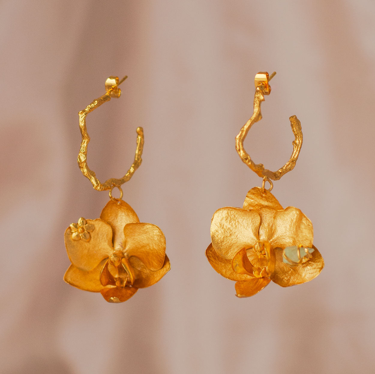 Aretes Candonga Orquídea Phalaenopsis Esmeralda en bronce bañado en oro de 24k, destacando flores naturales y esmeraldas colombianas