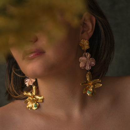 Detalle de los aretes con flores de orquídea y hojas de hiedra en oro, complementados con esmeraldas colombianas